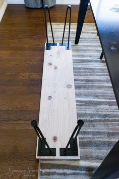 a piece of wood sitting on top of a hard wood floor next to a rug