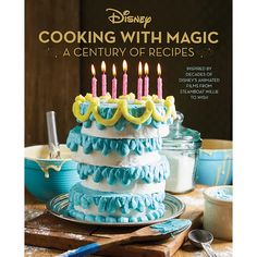 the cover of cooking with magic a century of recipes, featuring a cake with lit candles