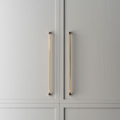 two wooden handles on the front of a white cabinet