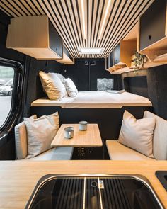 the interior of a camper with couches, tables and storage compartments on each side