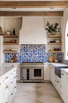 a kitchen with white cabinets and blue tile backsplashes on the wall above the stove