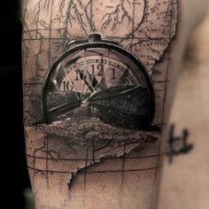 a man's arm with a compass tattoo on it and an old world map