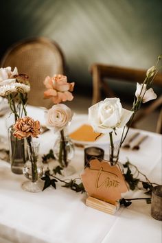 flowers in vases are sitting on a white table cloth with the word love written on it