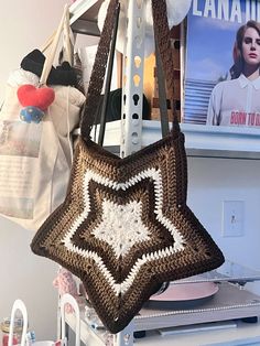 a crocheted bag hanging from a hook on a shelf next to other purses