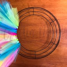 a colorful tutule is placed in front of a wire wreath on a wooden table