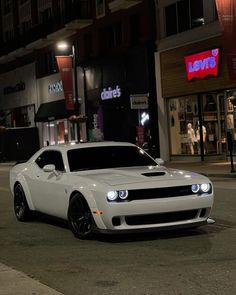 a white car is parked on the street at night