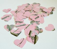 pink heart shaped confettis are scattered on a white surface