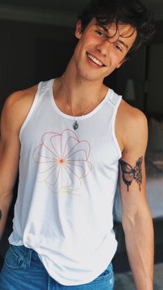 a young man wearing a white tank top with a flower design on it's chest