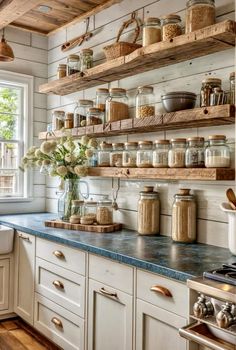 a kitchen filled with lots of open shelving and wooden shelves next to a window