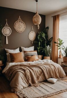 a bed with pillows and blankets on top of it in front of two potted plants