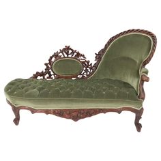 an antique chaise lounge with green velvet upholster and carved wood frame,