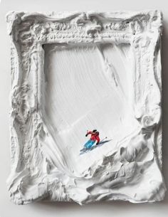 a white frame with a painting of a skier in the snow on it's side