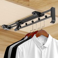 clothes hangers are hanging on the rail in front of a white shirt and black pants