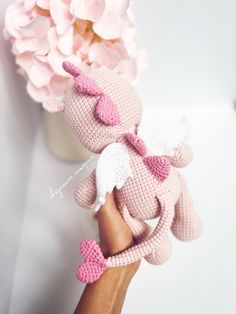 a crocheted pink teddy bear with white wings