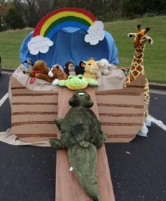 a table with stuffed animals on it in the middle of a parking lot next to a rainbow tent