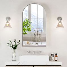 a bathroom with a sink, mirror and vase on the counter next to the bathtub