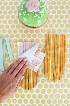 the person is making paper flowers out of napkins on the table with yellow and white polka dots