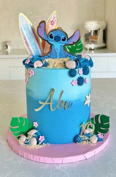 a blue and pink birthday cake with an image of stitching lillies on it