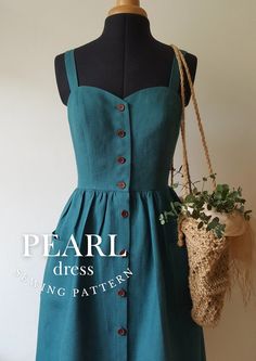 a green dress with buttons on the front and side, hanging from a mannequin