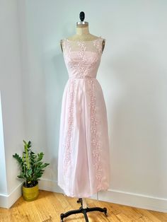 a dress on a mannequin with a plant in the corner next to it