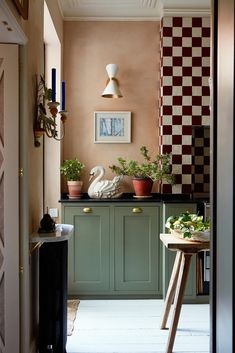 an open door leading to a kitchen with green cabinets and white floor tiles on the walls