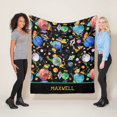 two women standing next to each other holding up a black blanket with planets on it