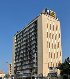 a tall building with lots of windows on the top and bottom floor, in front of a blue sky