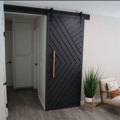 an open door leading to a living room with a chair and potted plant in the corner