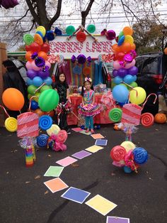 a woman standing in front of a carnival booth decorated with balloons and streamers on the ground