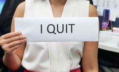 a woman holding up a piece of paper with the word i quit written on it