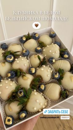 a box filled with lots of white chocolate covered in blueberries and topped with green leaves