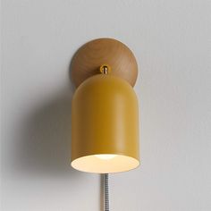 a yellow lamp on the wall next to a white wall with a wooden light fixture