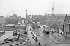 an old black and white photo of buses on the street