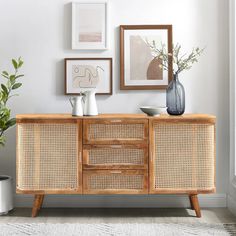 a wooden sideboard with wicker drawers and vases