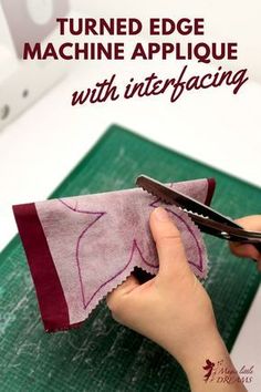 someone cutting fabric with scissors on top of a green board that says turned edge machine applique with interfacing