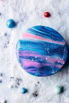 a blue and pink marble plate sitting on top of snow covered ground next to candy