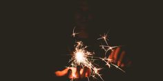 someone holding sparklers in their hands at night