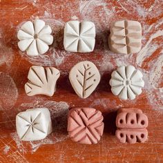 six clay molds with different shapes and sizes on a wooden surface, including leaves