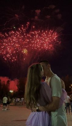 a man and woman kissing in front of fireworks