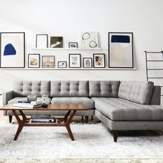 a living room filled with furniture and framed pictures on the wall above it's coffee table