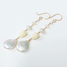 "Neutral and dainty Hawaiian style earrings featuring fresh water pearls , Ethiopian opal and pikake beads. Fresh water pearls are 12-14mm in size. Resin pikake beads are approximately 7-8 mm. Earrings length is approximately 2\" not including ear wires. Hand shaped 14k gold filled French ear wires. PLEASE NOTE: As you can see in the photos there are naturally occurring blemishes that give these pearls characters. These are stock photos so pearls are vary in shape and color." Delicate White Briolette Earrings, White Briolette Pearl Drop Earrings, White Pearl Charm Earrings, Ocean-inspired Shell-shaped Pearl Earrings, Elegant Shell-shaped Pearl Earrings, 14k Gold-filled Pearl White Dangle Pearl Earrings, Ethiopian Opal Earrings, Elegant 14k Gold-filled Earrings With Pearl Charm, Jewelry Safe