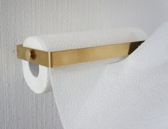 a roll of toilet paper hanging from a gold bar on a white wall with a wooden handle