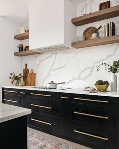 a kitchen with black cabinets and gold trimmings on the counter tops, along with wooden shelves