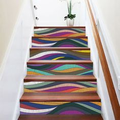 a stair case painted with colorful waves on it's sides and bottom, along with a plant in the middle