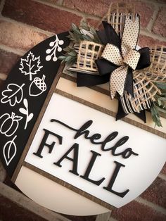 a sign that says hello fall hanging on the side of a brick wall next to a black and white wreath