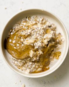 a bowl filled with food sitting on top of a white counter next to a spoon