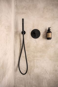 a bathroom with a black shower head and hand held soap dispenser