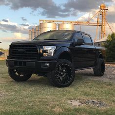 a black truck parked in front of a silo