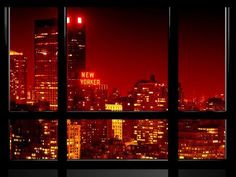 the city lights are lit up at night from an open window