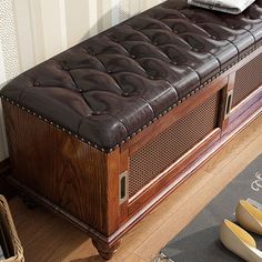 a brown leather bench sitting on top of a hard wood floor next to a wall